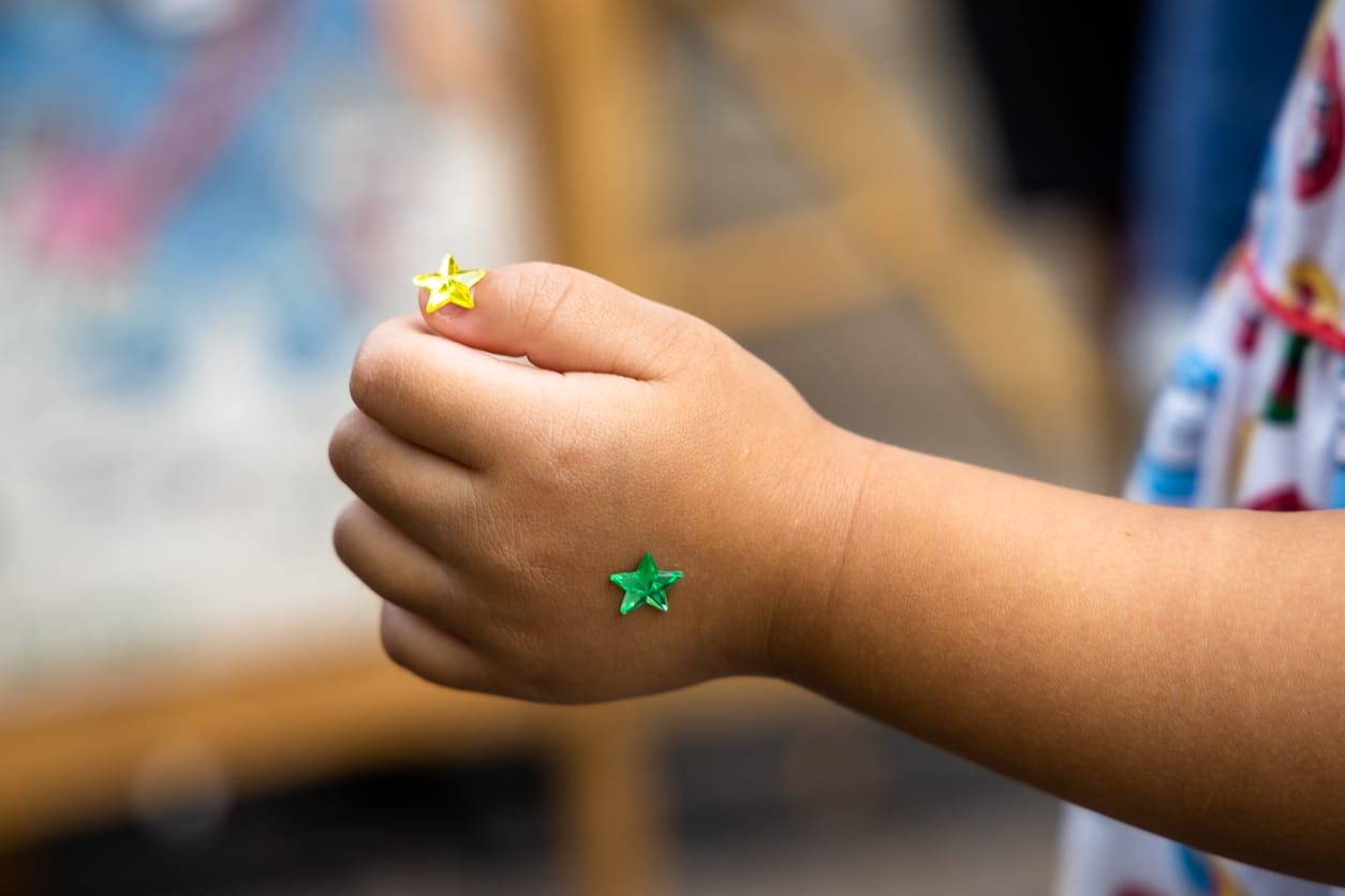 a baby hand with green and yellow star stickers